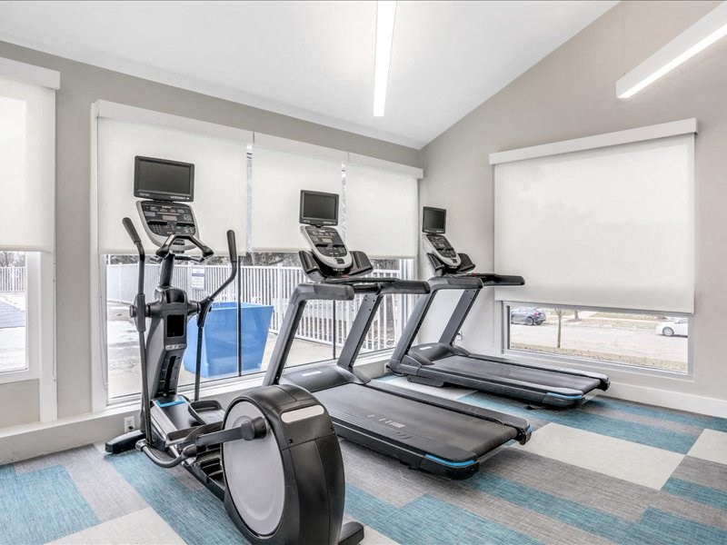 a gym with four treadmills and a pool